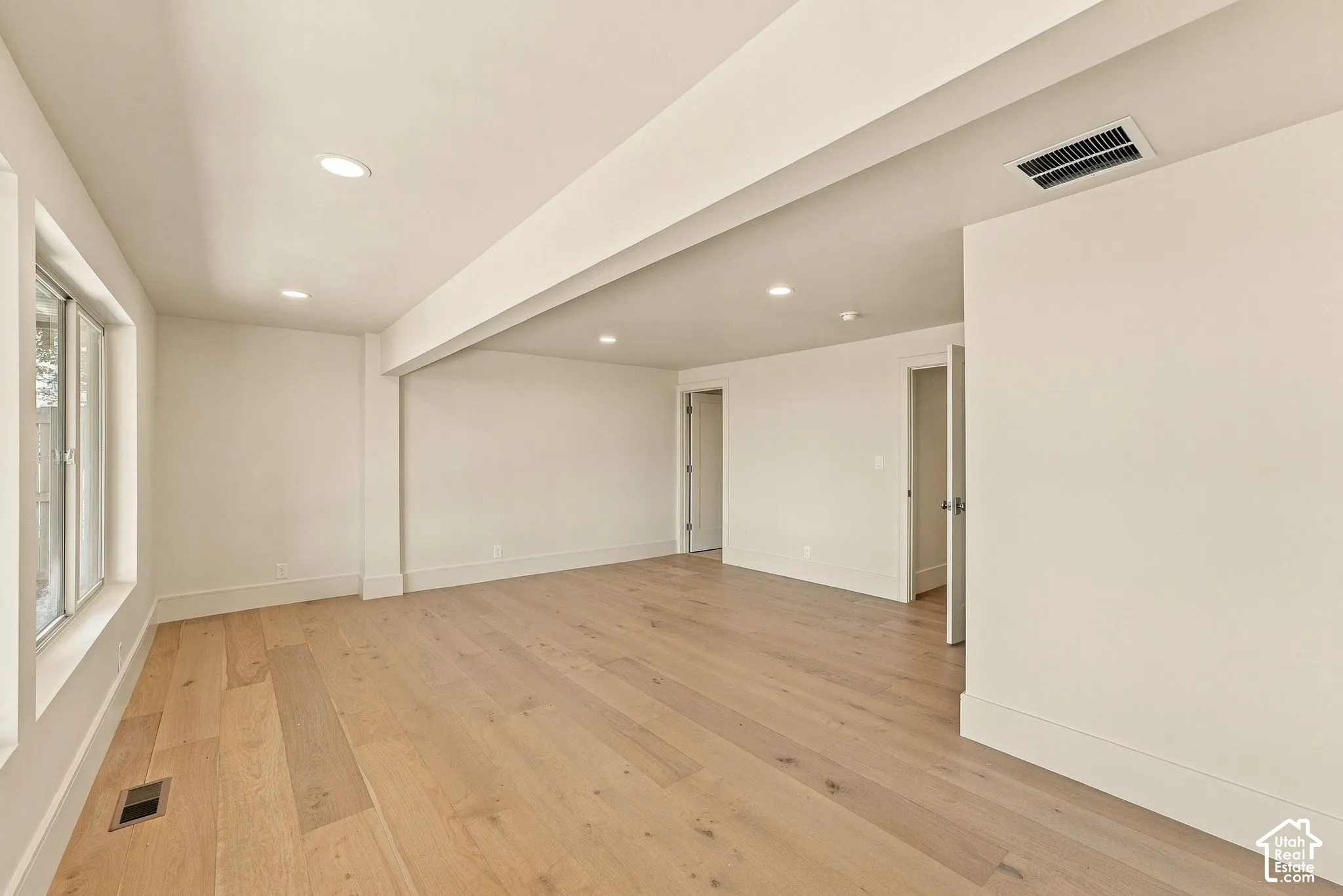 Neutral interior space featuring wood-finish flooring, recessed lighting, and multi-pane windows