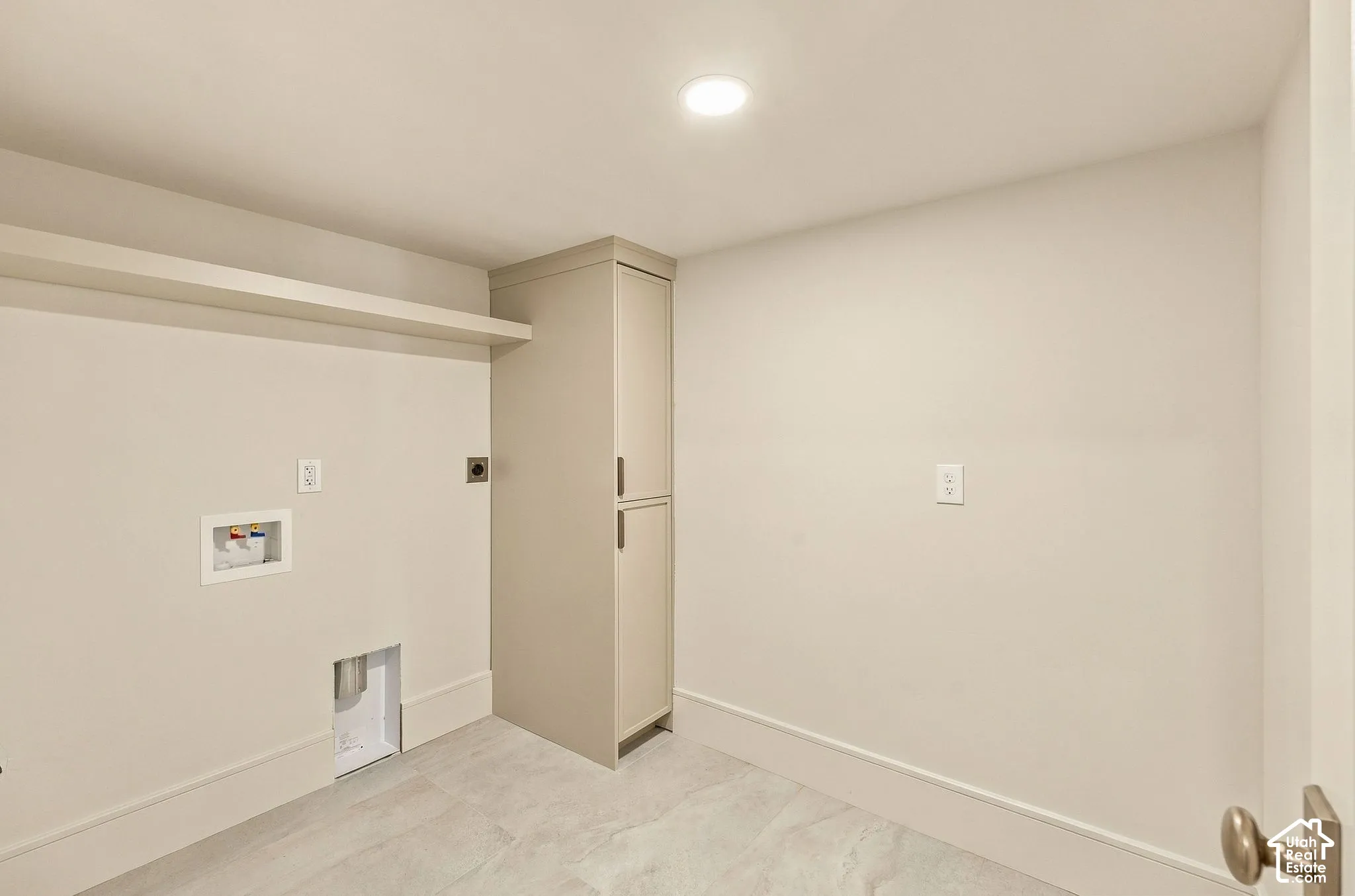 Utility space featuring stone-style tile flooring, tall built-in cabinetry, an overhead shelf, and recessed lighting