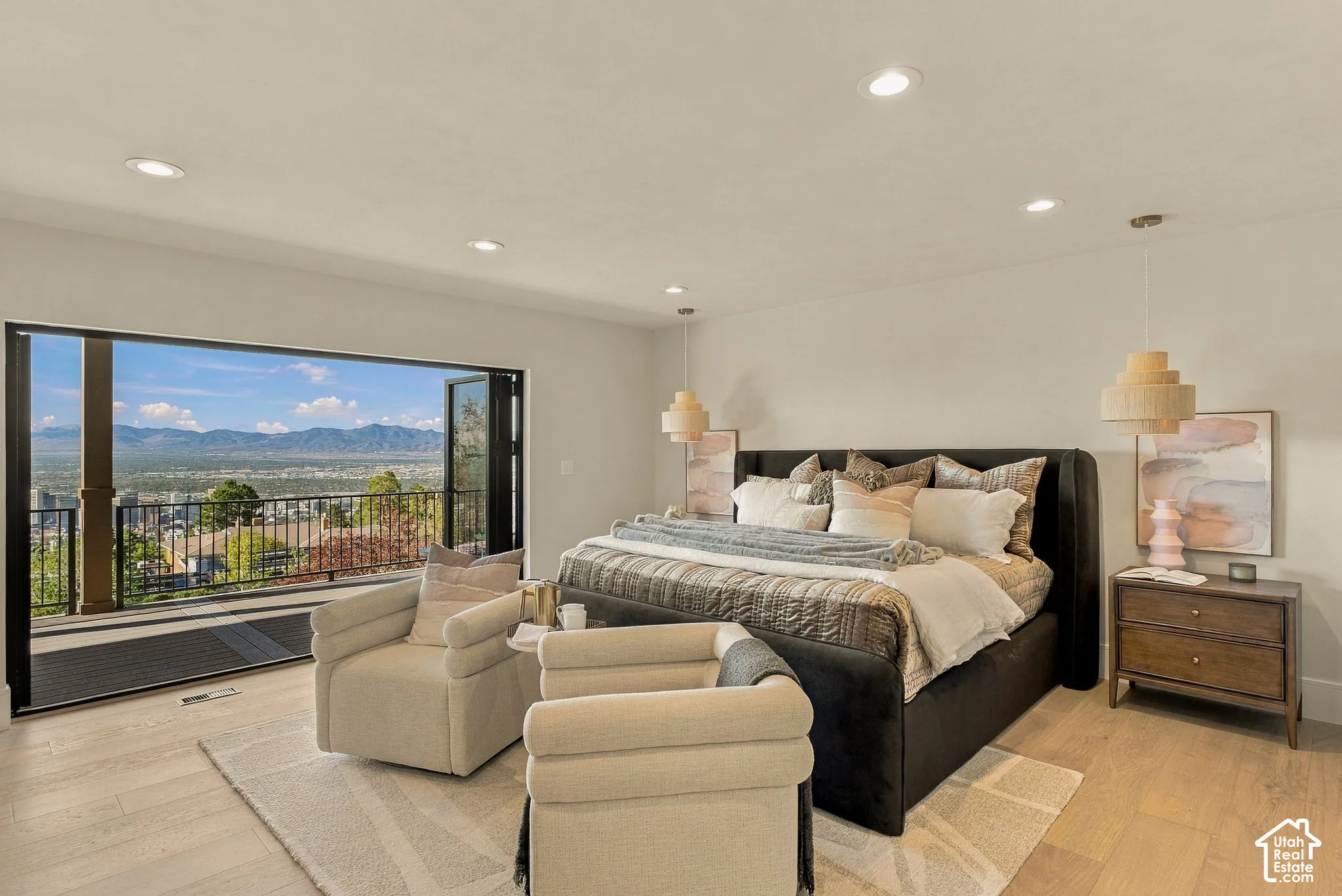 Open-concept interior featuring wood-finish flooring, recessed lighting, and a multi-panel sliding glass door leading to a balcony with mountain scenery