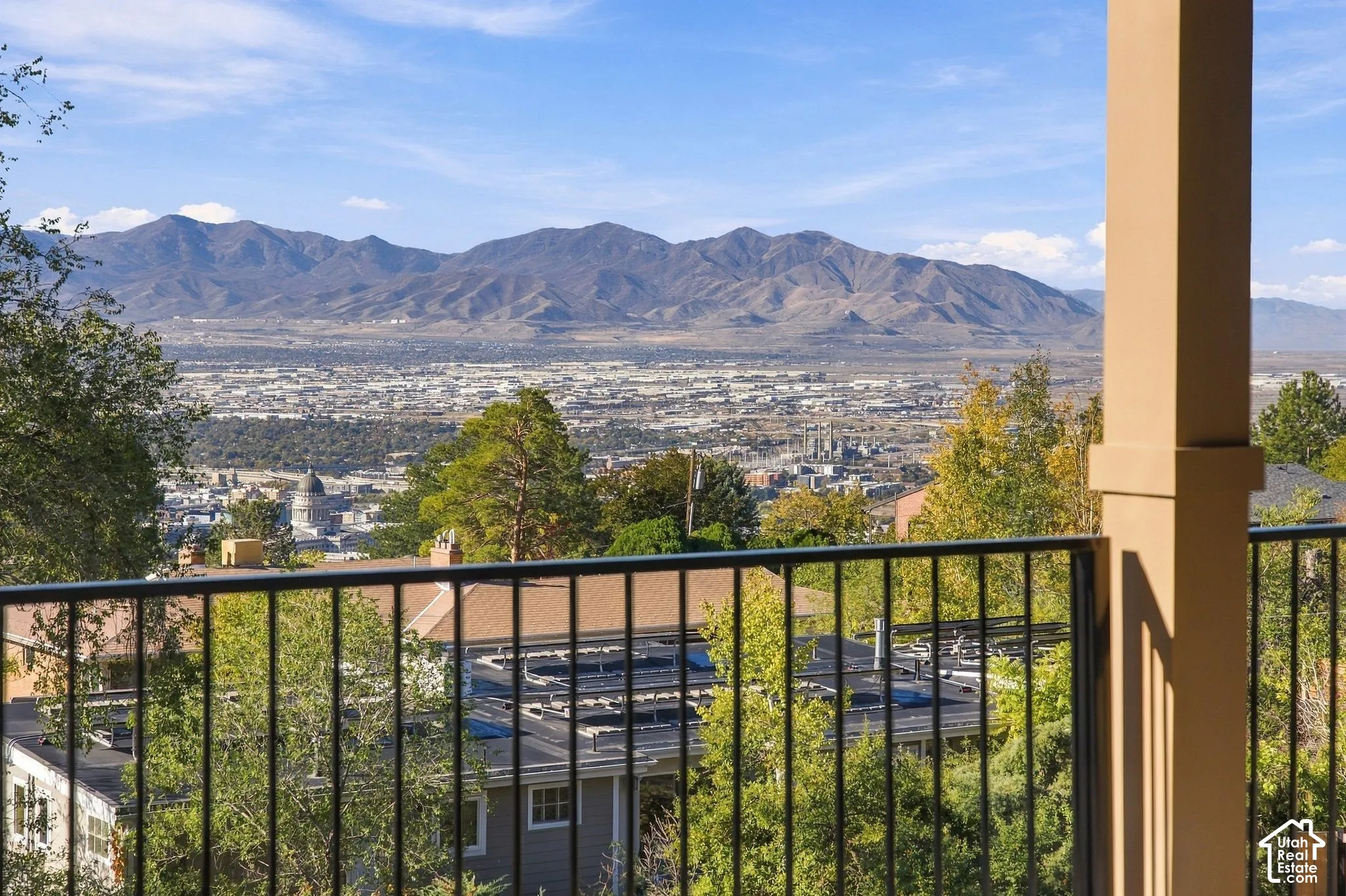 Elevated balcony featuring a black metal railing, support column, and expansive scenery of mountain ranges and the city below