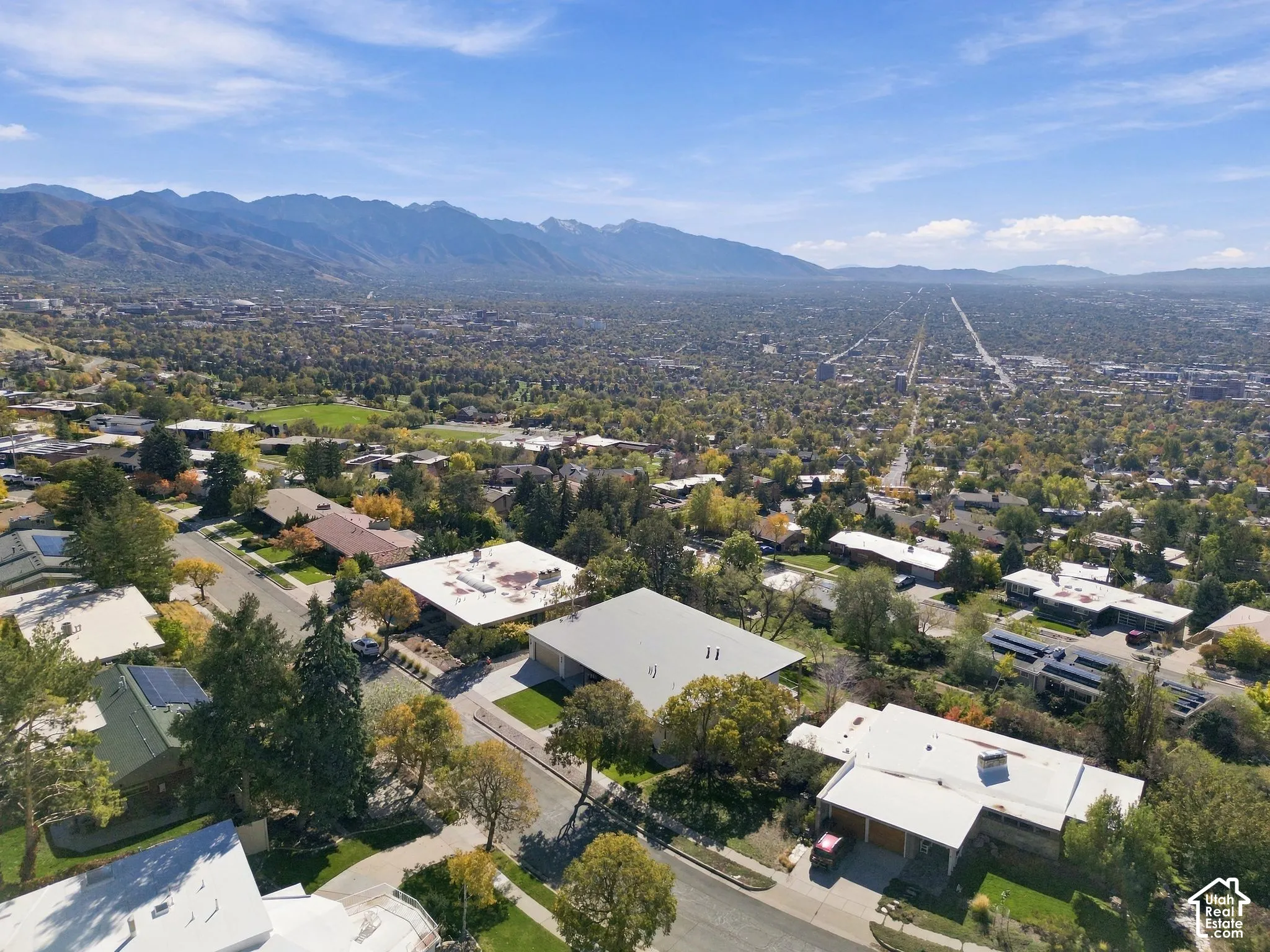 Aerial perspective featuring an expansive mountain backdrop and mature tree canopy throughout the residential landscape