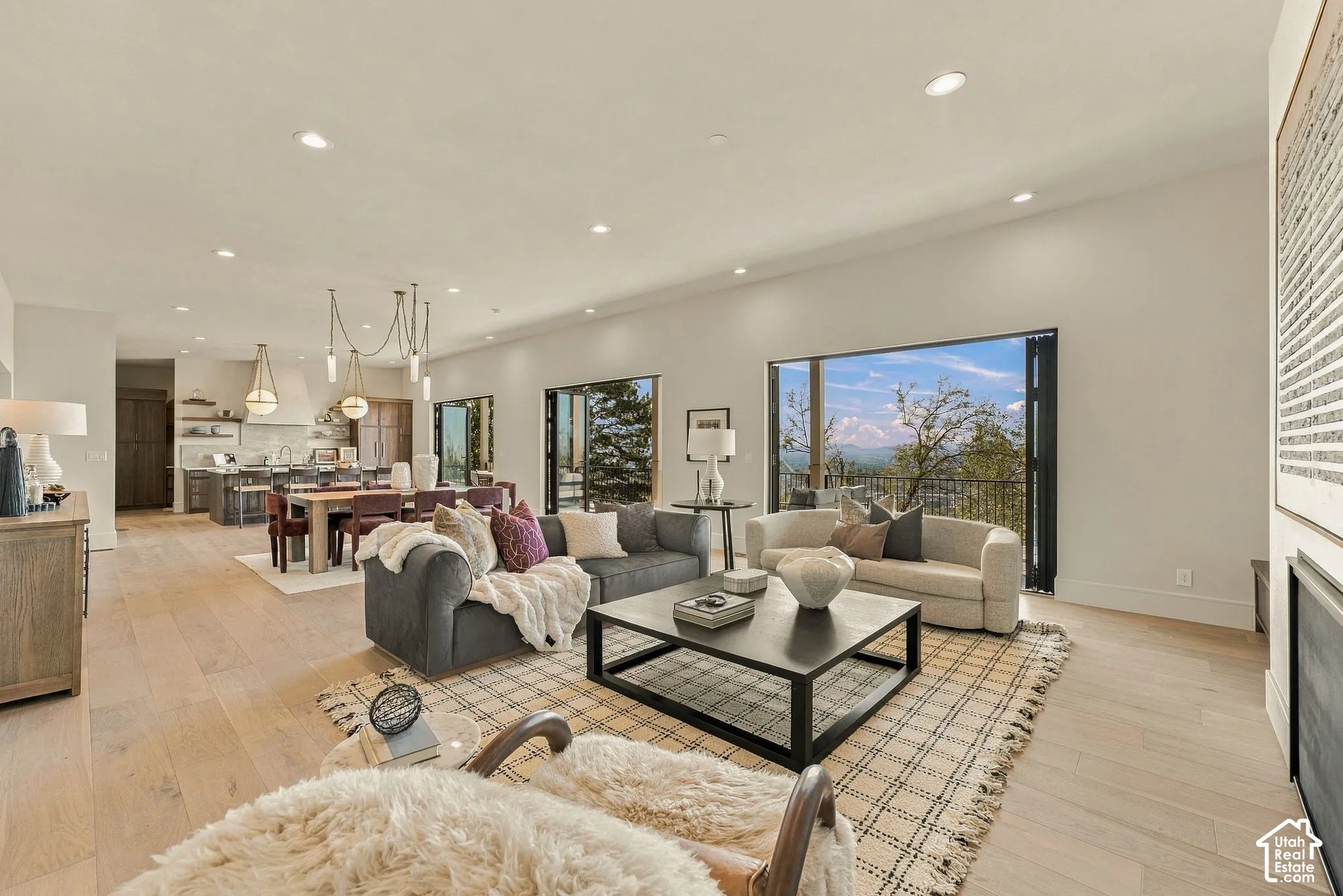 Open-concept floor plan featuring wood-finish flooring, recessed lighting, expansive multi-panel sliding glass doors, and panoramic mountain scenery