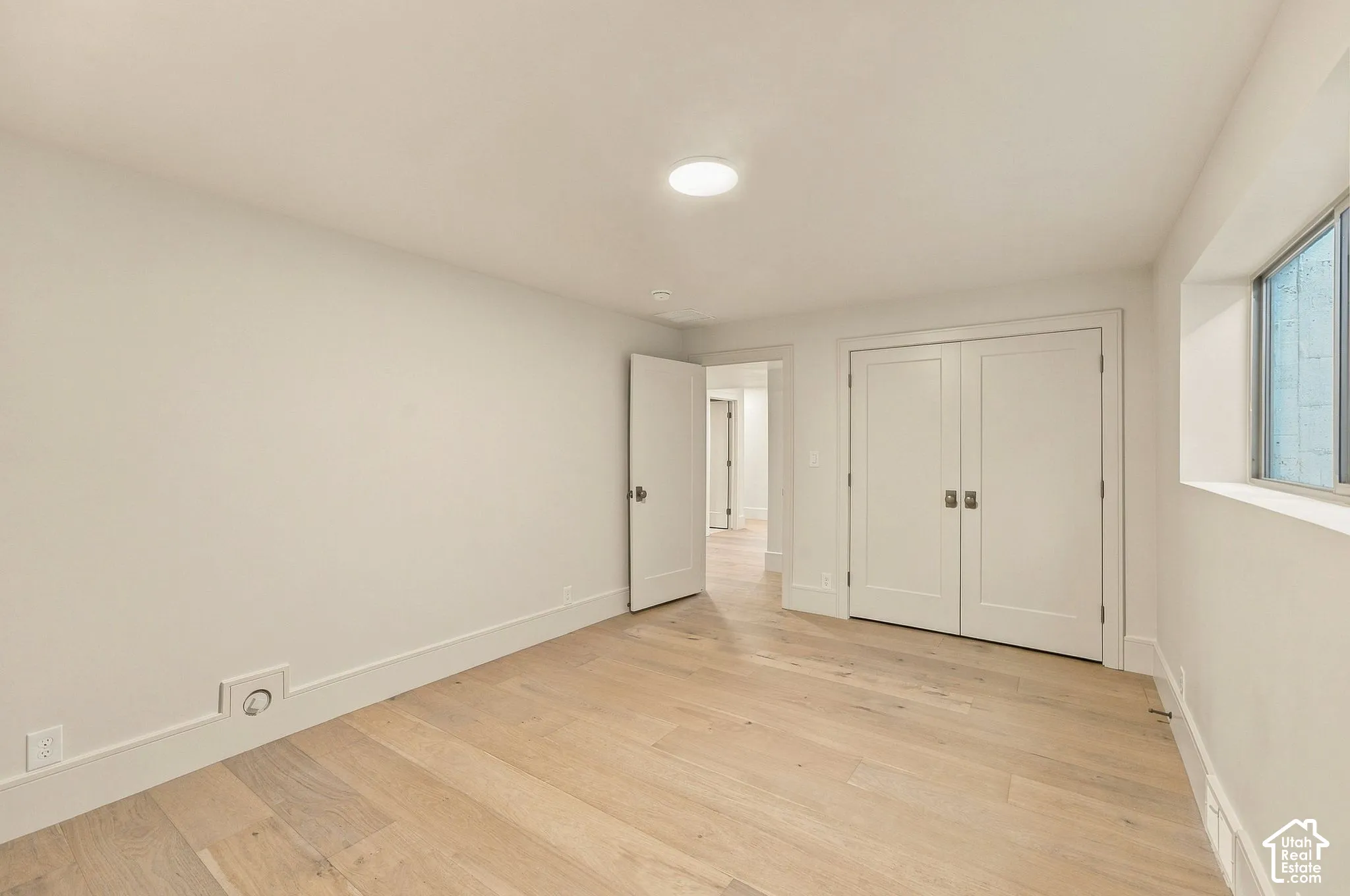 Interior room featuring wood-finish flooring, white walls, dual-panel closet doors, and recessed lighting