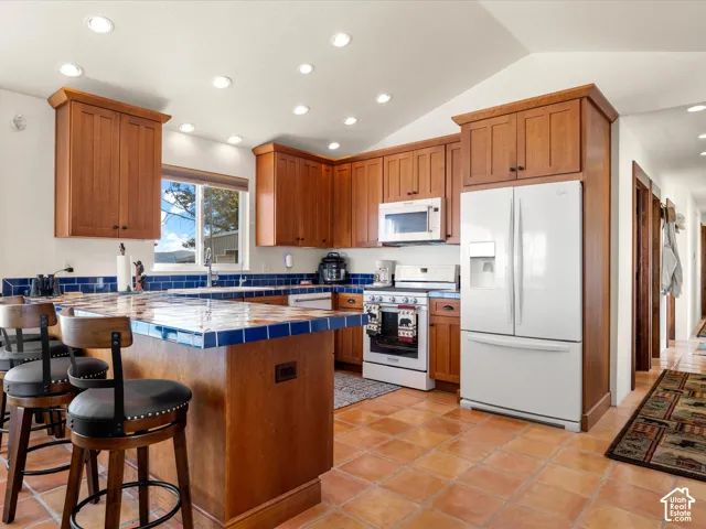 Kitchen featuring natural wood cabinetry, tiled countertops, a tiled backsplash, built-in appliances, and recessed lighting