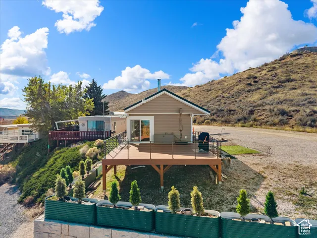 Elevated deck with horizontal cable railing, neutral-toned lap siding, mountain backdrop, and tiered metal garden planters