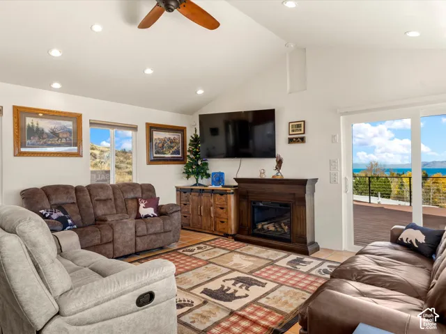 Vaulted ceilings with recessed lighting, stained wood-finish fireplace mantel, ceiling fan, and sliding glass doors with access to an exterior deck