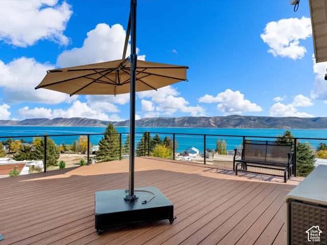 Expansive exterior deck featuring composite decking, black metal railings, and mountain and water scenery