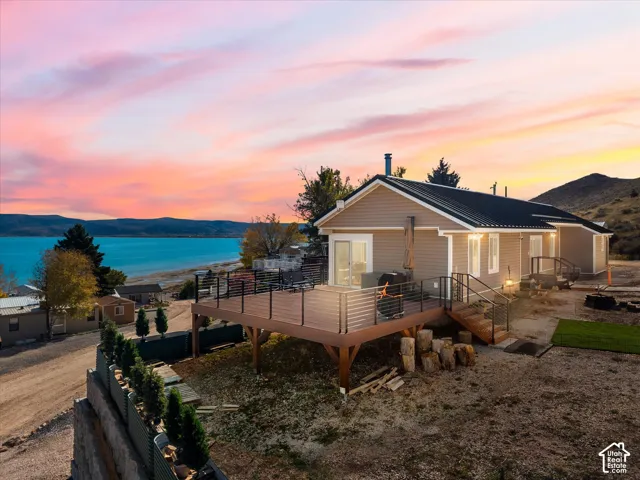Raised exterior deck featuring composite decking and horizontal cable railing, complemented by lap siding, a metal roof, and an expansive mountain and water landscape