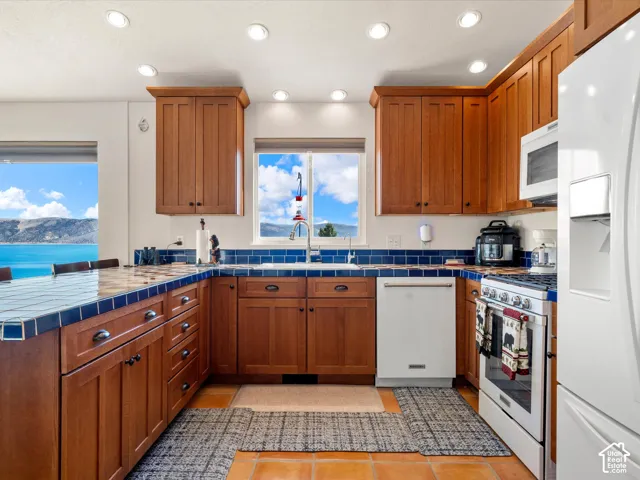 Kitchen featuring stained wood cabinetry, tile countertops with matching backsplash, recessed lighting, and built-in appliances