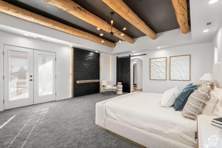 Exposed natural wood ceiling beams, dark contrasting ceiling finish, black shiplap accent wall with built-in mantel, black sliding barn door, and glass-paneled exterior doors