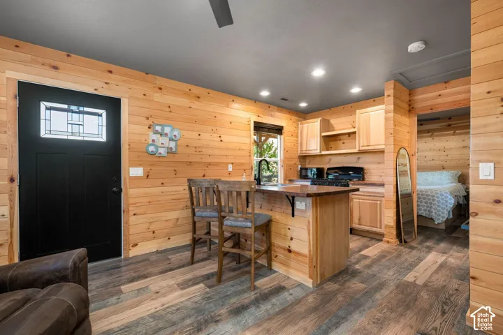 Natural wood-paneled walls, wood-finish flooring, recessed lighting, and a breakfast bar with a dark-toned countertop