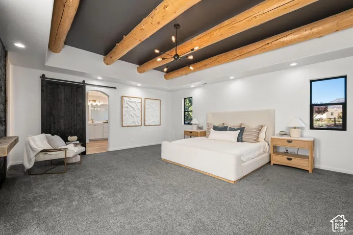 Exposed natural wood ceiling beams, coffered ceiling detail, matte black sliding barn door, recessed lighting, and expansive windows