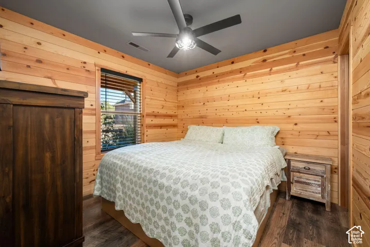 Horizontal wood paneling, wood-finish flooring, dark-toned ceiling, and multi-blade ceiling fan with integrated light fixture