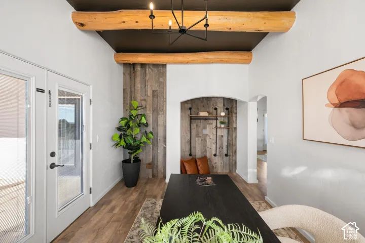 Entry area featuring exposed natural wood ceiling beams, a dark-toned ceiling, vertical wood-plank wall accents, and an arched recessed alcove with integrated metal shelving