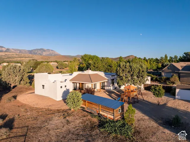 Stucco exterior featuring a covered patio, metal-roofed auxiliary structure, and mountain backdrop