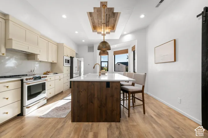 Kitchen featuring a central island with wood-finish cabinetry, quartz countertops, recessed ceiling detail with wood-plank inlay, and wood-finish flooring
