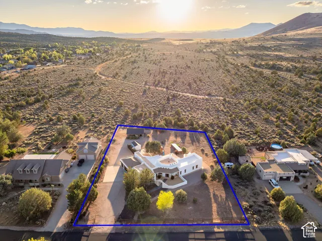 Pueblo-style architecture with flat roofing, expansive exterior lot with fencing, detached structure, and mountain scenery