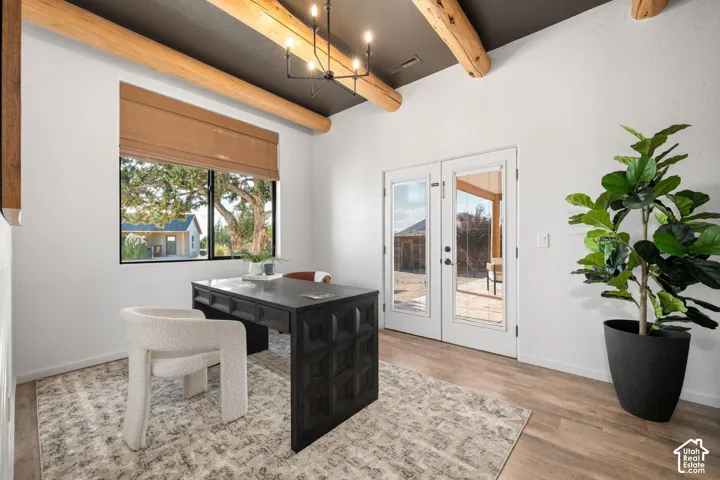Exposed natural wood ceiling beams, high-contrast dark ceiling finish, wood-finish flooring, metal multi-arm chandelier, and glass-paneled double doors
