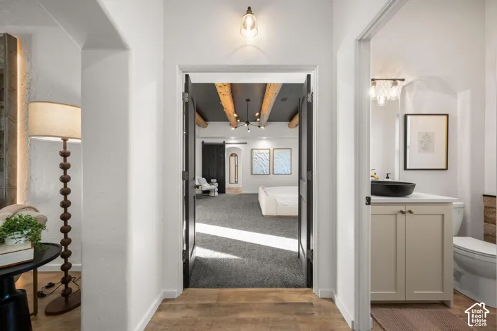 Entryway featuring wood-finish flooring, exposed ceiling beams, a modern vanity with a circular vessel sink, and double-door entry