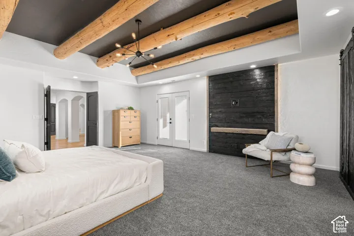 Exposed log ceiling beams, dark-stained horizontal plank accent wall, recessed lighting, chandelier fixture, and double glass-panel entry doors