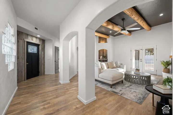 Entryway featuring wood-finish flooring, a glass block window, and vertical wood planking at the front door, incorporating arched architectural openings and a ceiling with exposed timber beams