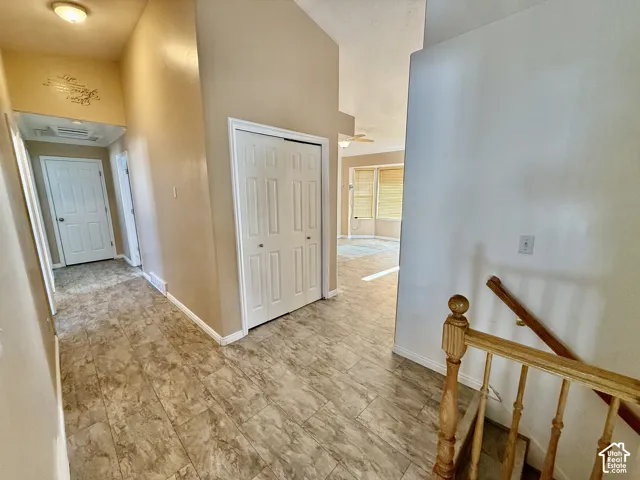 Entryway featuring vaulted ceilings, tile flooring, dual-door coat closet, and a wooden handrail with balusters
