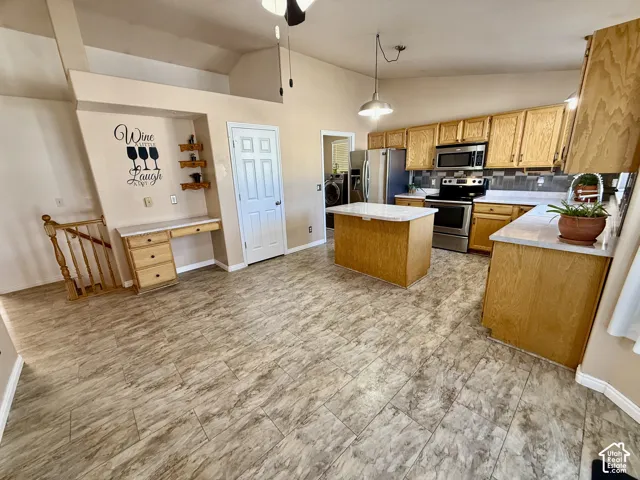Kitchen featuring natural-finish cabinetry, central island with stone-surface countertop, tiled flooring, vaulted ceiling, and built-in desk area
