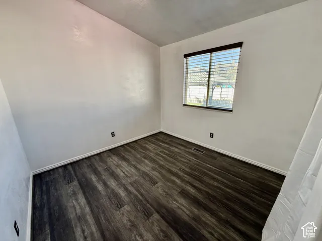 Room featuring wood-finish flooring, neutral walls, and a single-pane window with installed horizontal blinds