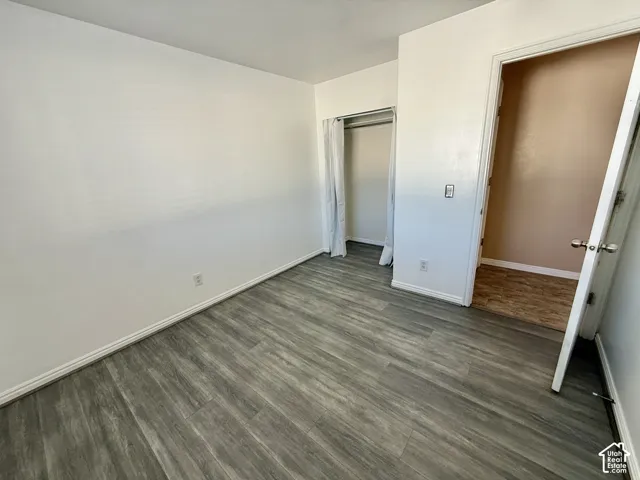 Neutral interior featuring wood-finish flooring, white walls, and a recessed closet area