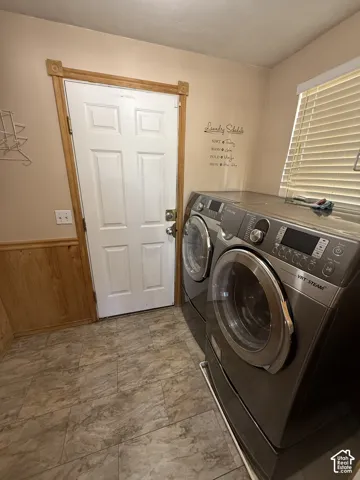 Laundry room featuring tile flooring, wainscoting, and a paneled door with wood trim