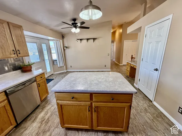 Kitchen featuring wood cabinetry, central island with a stone-finish countertop, stainless steel dishwasher, vaulted ceiling with integrated lighting, and wood-finish flooring