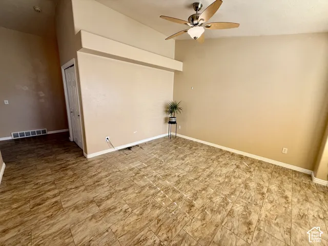 Vaulted ceilings, neutral wall tones, tile flooring, and a five-blade ceiling fan with integrated light fixture