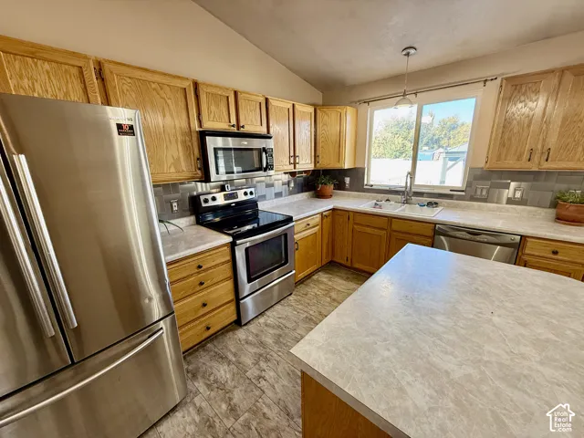 Kitchen featuring wood cabinetry, stone-finish countertops, stainless steel appliances, tiled backsplash, and center island