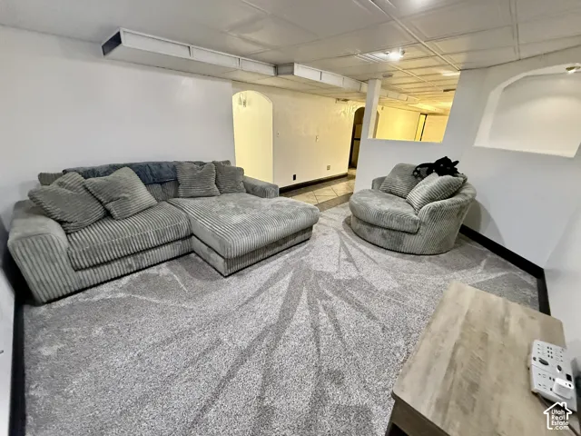 Finished interior space featuring textured carpeting, suspended ceiling panels, arched doorways, and a recessed wall niche