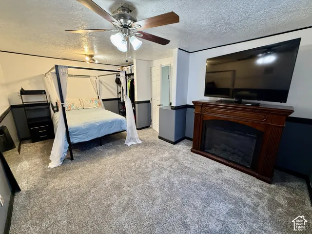 Interior space featuring wall-to-wall carpeting, a built-in decorative fireplace mantel, two-tone wall finish with integrated chair rail, and a multi-blade ceiling fan with integrated lighting