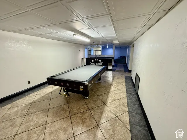 Finished space featuring tile flooring with decorative stone-look inlay, a grid ceiling, and a built-in counter