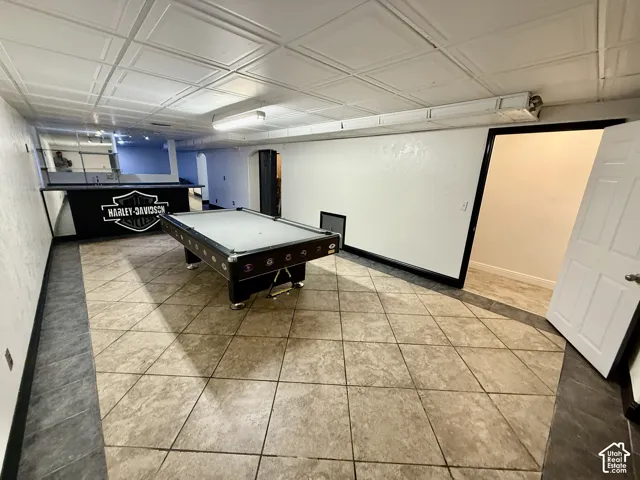 Multi-purpose room featuring a built-in wet bar, square-tiled flooring with a contrasting border, and coffered ceiling panels
