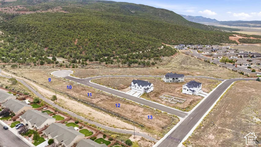 Aerial perspective of residential land parcels featuring paved streets, utility infrastructure, and mountain topography