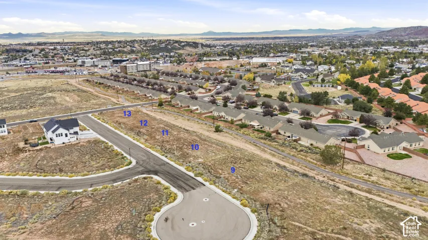 Aerial perspective of numbered vacant lots featuring paved street access, concrete curbing, and mountain backdrop