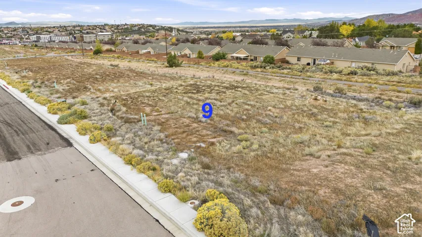 Vacant residential lot featuring paved street access, concrete curbing, and mountain backdrop