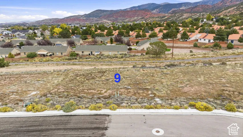 Vacant residential lot featuring paved street access, concrete curbing, and prominent mountain backdrop
