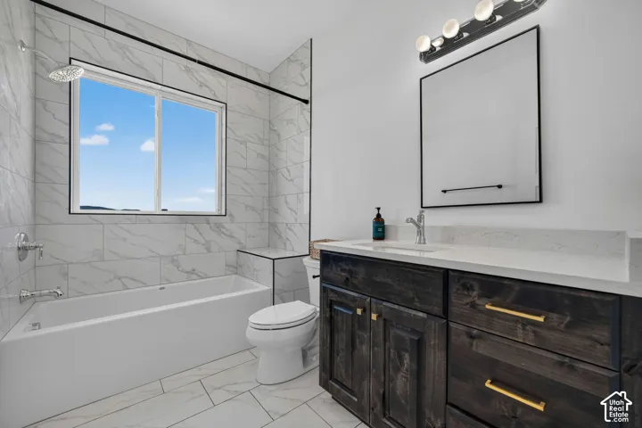 Bathroom featuring stone-finish wall tile, a dark-stained wood vanity with quartz countertop, a framed vanity mirror, and polished metal fixtures