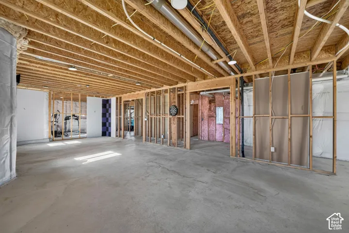 Unfinished lower level featuring exposed wood joist ceilings, concrete flooring, and timber-framed partition walls with fiberglass insulation