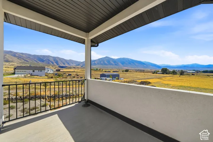 Covered balcony featuring a metal railing, concrete flooring, and an expansive mountainous landscape backdrop