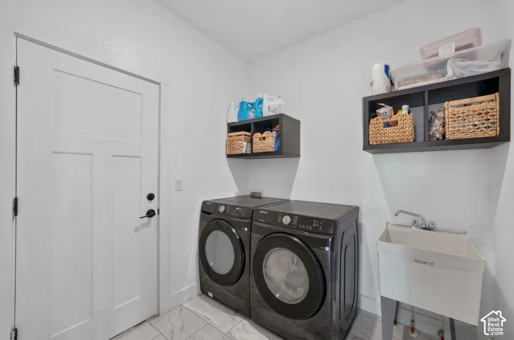 Laundry space featuring tile flooring, a utility sink, and wall-mounted storage cabinetry