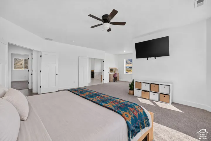 Spacious bedroom featuring wall-to-wall carpeting, shaker-style interior doors, and a ceiling fan with integrated lighting