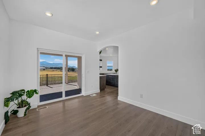 Wood-finish flooring, recessed lighting, sliding glass door, and an arched entryway with mountain scenery