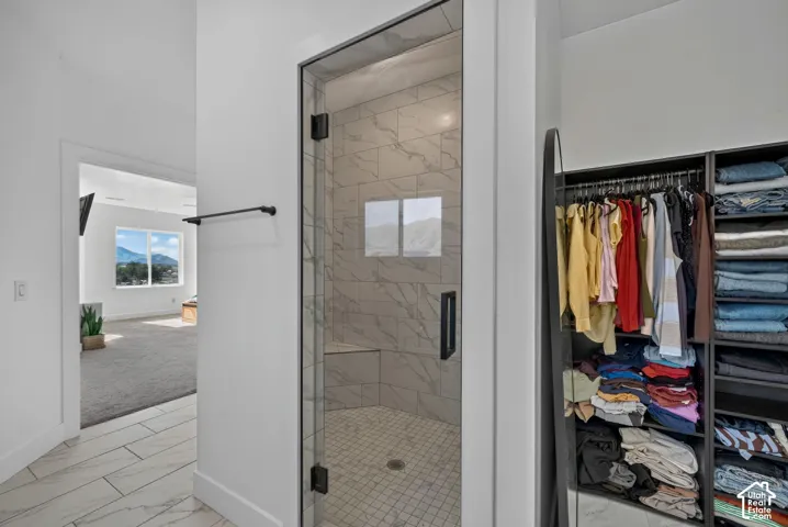Walk-in shower featuring large-format tile walls with a built-in bench, glass enclosure with matte black hardware, and tile flooring