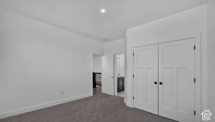 Neutral-toned wall-to-wall carpeting, recessed ceiling lighting, and double-door closet with shaker-style panels