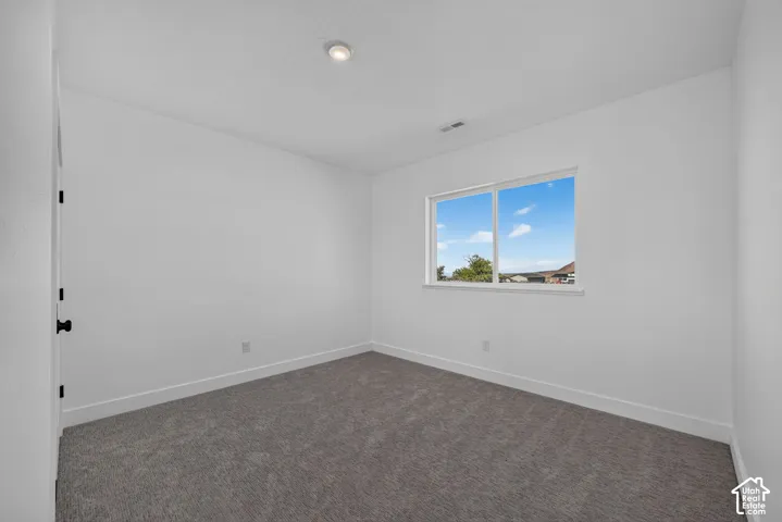 Neutral interior featuring wall-to-wall carpeting, crisp white wall finish, and a sliding window with outdoor exposure